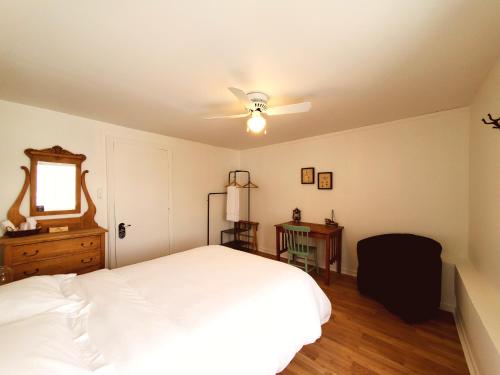 a bedroom with a white bed and a ceiling fan at Auberge de la rive de Charlevoix - Auberge de jeunesse familiale pour voyageurs de tous âges in Saint-Joseph-de-la-Rive