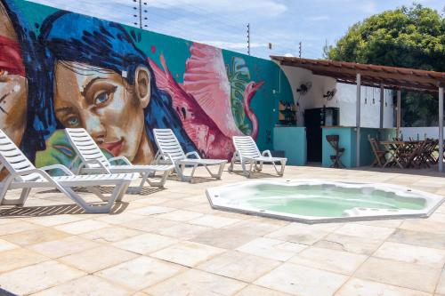 Salve Maloca Hostel في فورتاليزا: جدارية مع كراسي وحوض استحمام ساخن أمام مبنى