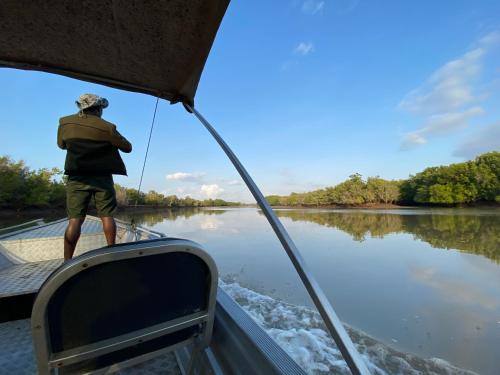 a man is standing on a boat on a river at Saadani Safari Lodge in Saadani