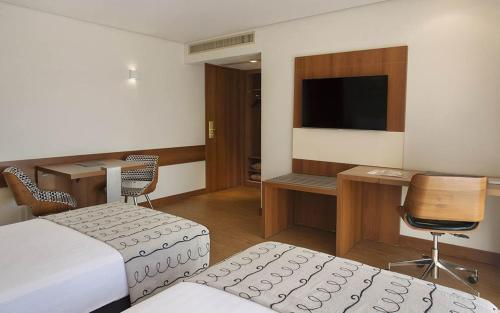 a hotel room with a bed and a desk and a television at Windsor Plaza Brasilia in Brasilia