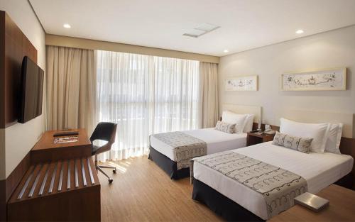 a hotel room with two beds and a television at Windsor Plaza Brasilia in Brasilia