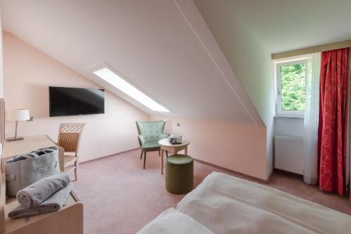 a bedroom with a bed and a desk and a tv at Robenstein Aktivhotel & SPA in Zwiesel