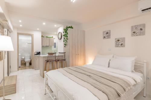 una camera bianca con un grande letto e una cucina di Cute Love-nest with Patio in the Heart of Kolonaki ad Atene