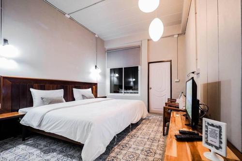 a bedroom with a bed and a desk with a television at Thaimueang Boutique Hotel in Thai Muang