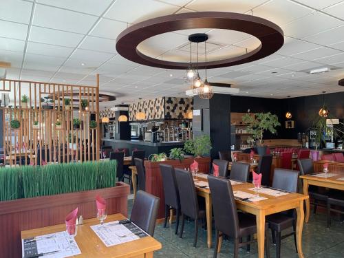 uma sala de jantar com mesas e cadeiras de madeira em Hôtel Restaurant Kyriad Direct DIJON NORD - Zenith - Toison d'Or em Dijon