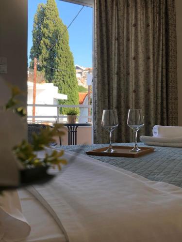 two wine glasses on a table in a room with a window at Studio Nefeli - Heart of Archangelos in Archangelos