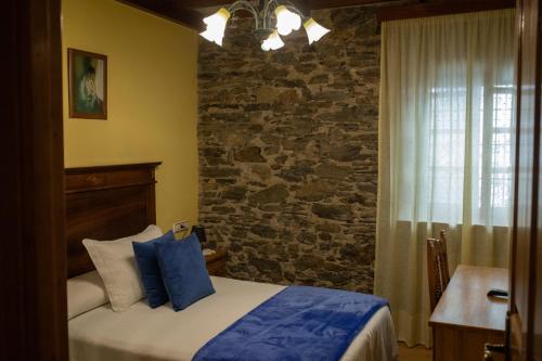 um quarto com uma cama e uma parede de pedra em Apartamentos Rurales Las Mestas em Puenteciella