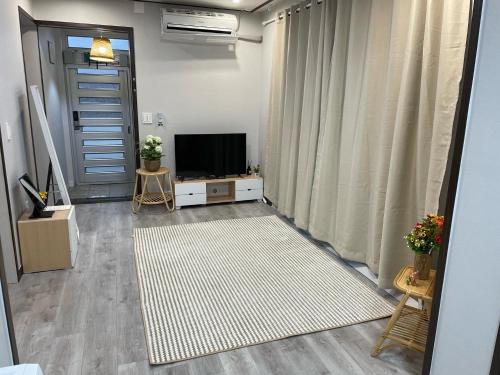 a living room with a flat screen tv and a door at Cozy Sinchon 2548 in Jeju