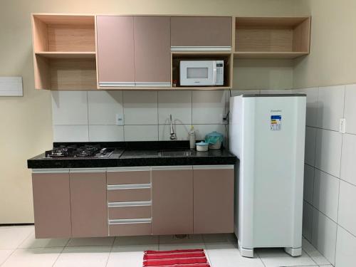 a kitchen with a white refrigerator and a microwave at Residencial Milagre 202 in Juazeiro do Norte