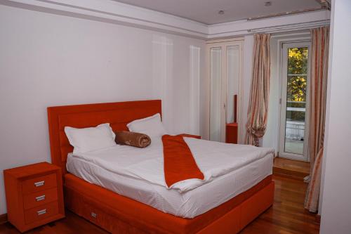 a bedroom with a bed with an orange blanket on it at Villa Dedinje in Belgrade