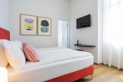 Dieses weiße Zimmer verfügt über ein Bett und einen TV. in der Unterkunft Villa Rossella in Locarno