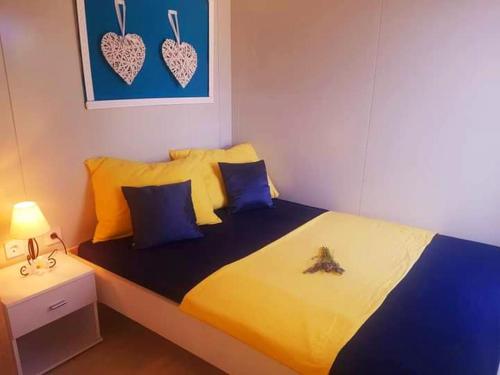 1 dormitorio con 1 cama con almohadas amarillas y azules en Eden Lady Mobile Home, Croatia, Drage, en Drage