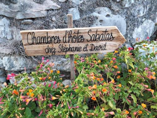 a sign in the middle of a garden with flowers at Chambre d'hôtes La terrasse de Sabatas in Chomérac
