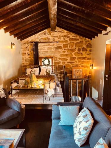 a living room with a couch and a stone wall at Palheiro Mezio in Mezio