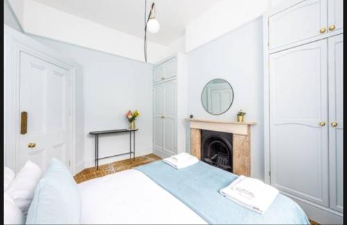 biała sypialnia z łóżkiem i kominkiem w obiekcie Lovely 1-bedroom flat in Chelsea w Londynie