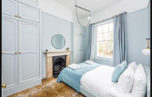 a blue bedroom with a bed and a fireplace at Lovely 1-bedroom flat in Chelsea in London