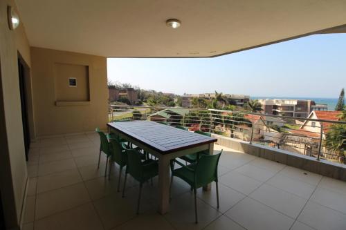 una mesa y sillas en un balcón con vistas en Saints View Resort Unit 17, en Uvongo Beach