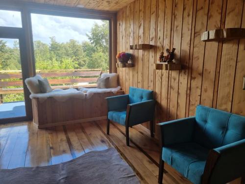 a living room with two chairs and a large window at PARCELA DE AGRADO CON PISCINA LAGO RANCO todas las instalaciones con uso exclusivo capacidad 20 personas in Lago Ranco