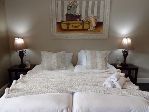 two white beds in a room with two lamps at Waves Guest House in Jeffreys Bay