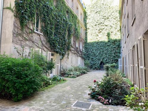 Une allée avec du lierre sur le côté d'un bâtiment dans l'établissement Chambre d’hôtes - Marais, à Paris