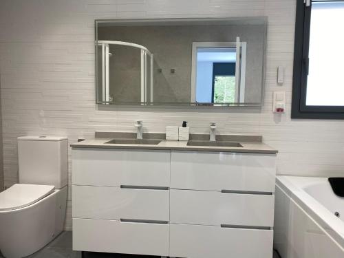 W łazience znajduje się umywalka, toaleta i lustro. w obiekcie Lux@Spa w mieście Vallirana