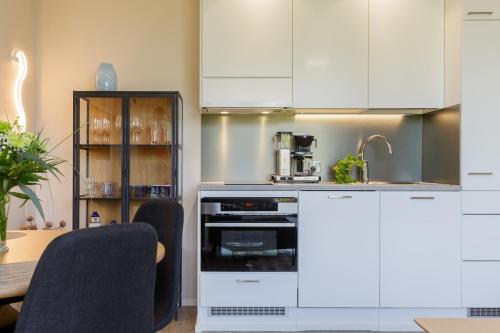 une cuisine avec des placards blancs et une table avec des chaises dans l'établissement Apartment Marinan Portti B37 kaksio Kalajoki, à Kalajoki