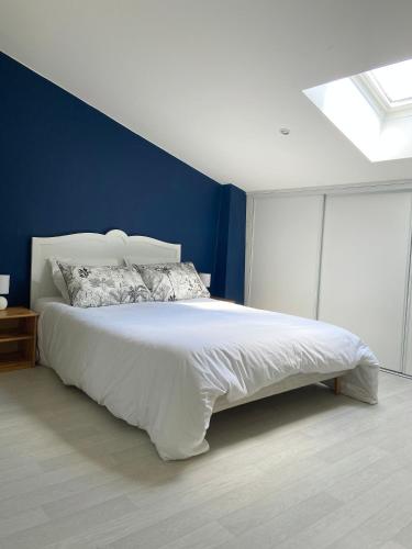a bedroom with a large white bed with a blue wall at Maison de campagne in Rions