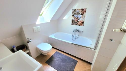 a white bathroom with a tub and a toilet at Apartamenty 4 Góry in Szczyrk