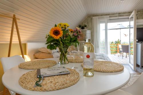 una mesa con una botella de vino y un jarrón de flores en Szőlőhegy Vendégház Sümeg, en Sümeg