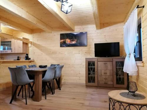 a dining room with a table and chairs and a tv at Agroturystyka W oddali z balią in Międzylesie