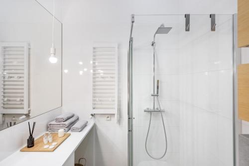 a white bathroom with a shower and a sink at Kraków Loft in Krakow