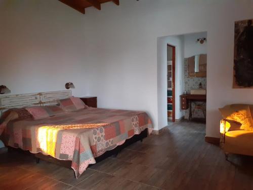 1 dormitorio con 1 cama y 1 silla en una habitación en Basilia - Casas de campo en Ruiz