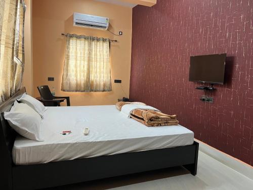 ein Schlafzimmer mit einem Bett und einem Fernseher an der Wand in der Unterkunft Hotel Krishna Paradise in Deoghar