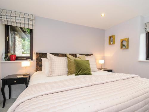 a bedroom with a large white bed with green pillows at Lydgate House Cottage in Yelverton