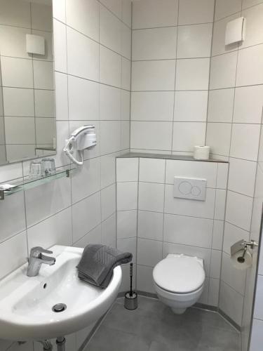 a white bathroom with a toilet and a sink at Gasthof Adler Äpfingen in Äpfingen