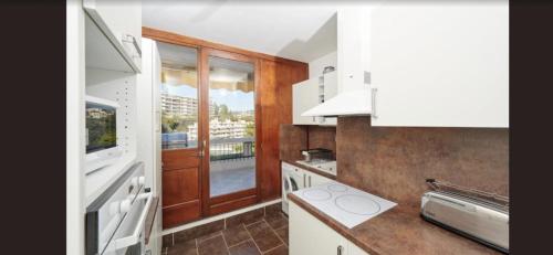 a kitchen with white cabinets and a large window at Dernier Etage d'exception in Nice