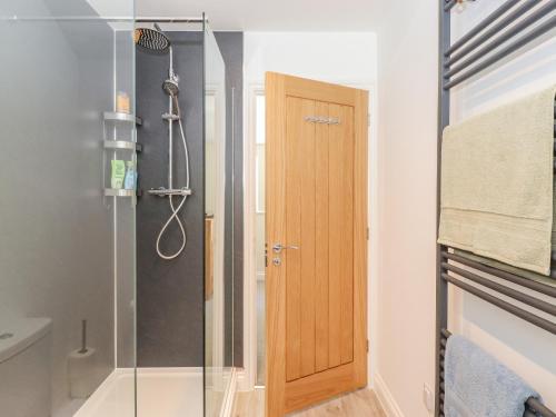 a bathroom with a shower and a wooden door at Ladstock Cottage in Keswick