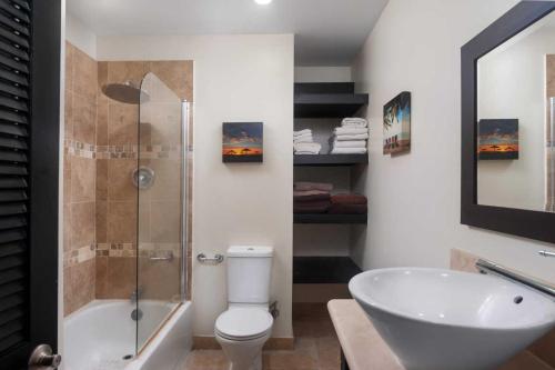 y baño con ducha, aseo y lavamanos. en Wonderful 1-bed condo, 2min walk to beach & more, en Bridgetown