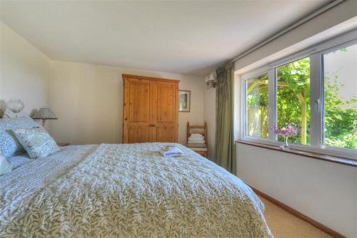 a bedroom with a large bed and a window at Willows in Charmouth