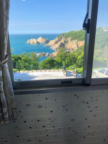 a window with a view of a beach and the ocean at Home run Homestay in Dongyin