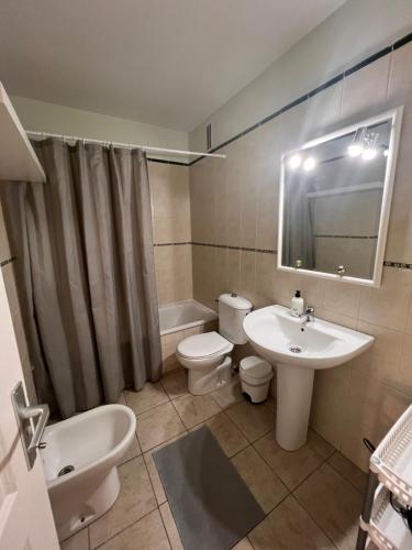 Un baño con lavabo, inodoro y espejo. en Jardín, en Puerto de Santiago