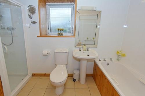 a bathroom with a toilet and a sink and a tub at Canach Cottage in Pollachar