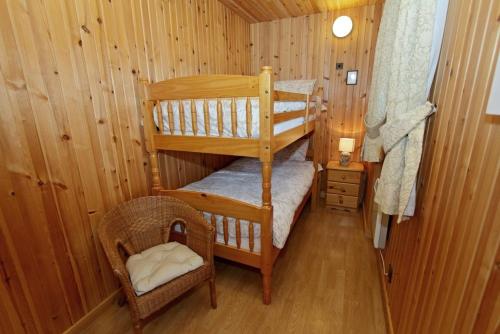 a small room with two bunk beds and a chair at Canach Cottage in Pollachar