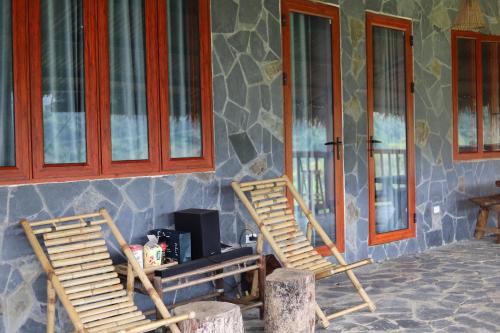 two wooden chairs sitting in front of a house at Mộc Châu Peachy Garden in An Pon