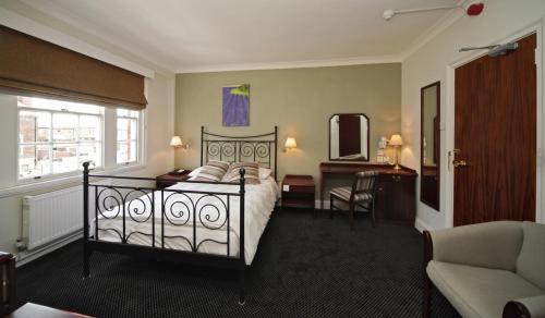 um quarto com uma cama, uma secretária e uma cadeira em The Broadway Hotel em Letchworth