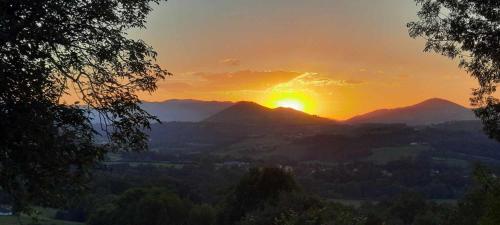 a sunset over a mountain range with the sun setting at Gîte des 3 arbres in Aramits