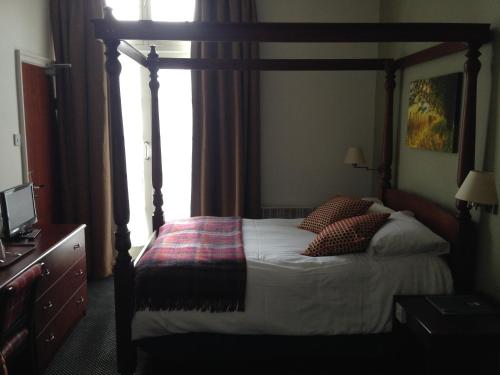 a bedroom with a wooden canopy bed with pillows at The Broadway Hotel in Letchworth