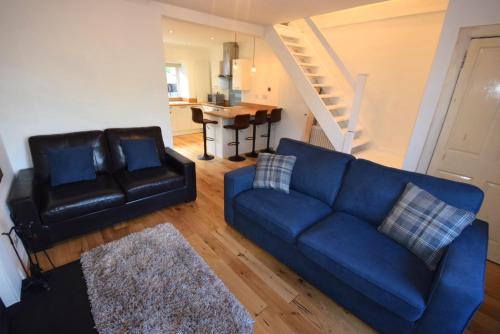 a living room with a blue couch and a chair at 1 Planetree Cottage - Loch View in Lochgoilhead