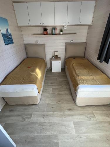 duas camas num pequeno quarto com armários brancos em Exklusives Ferienhaus Rybak mit Boxspringbetten direkt am Steinhuder Meer em Wunstorf