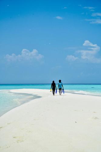 two people walking on the beach with their surfboards at La Cabana, Maamigili in Maamigili